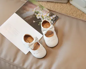 Nahaufnahme weißer Prinzessinnenschuhe für Kleinkinder mit Schleife und Wellenrand