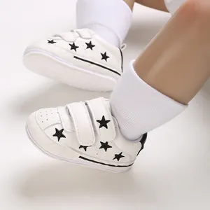 Close-up of white baby sneakers with black star embroidery and Velcro straps
