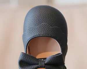 Detailansicht der schwarzen Kunstledertextur und Schleife an diesen Mädchen-Prinzessin-Schuhen