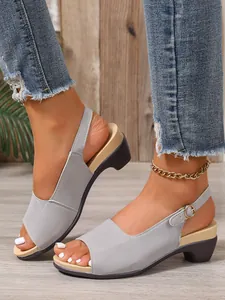 Detailweergave van grijze peep-toe sleehaksandalen met verstelbare gouden gespriem