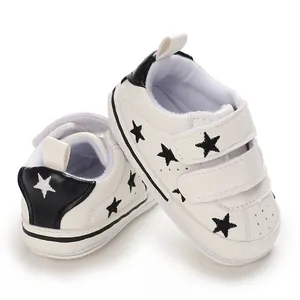 Close-up of stylish white baby sneakers with black star embroidery and hook straps