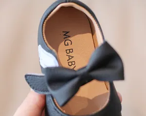 Detaillierte Nahaufnahme schwarzer Baby-Mädchen-Loafer mit dekorativer Schleife und Sohle.