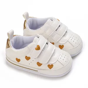White infant sneakers with golden heart embroidery and double velcro straps for easy wear