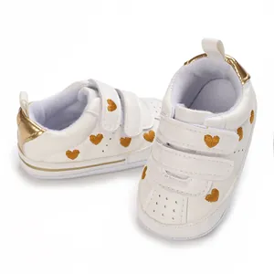 Adorable white infant sneakers featuring gold heart embroidery and convenient velcro straps