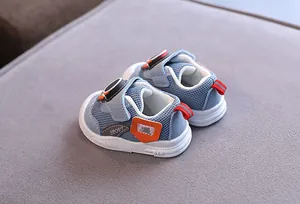 Dettaglio scarpe da camminata per neonati in mesh azzurro con fibbia rotante e arancione.