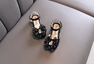 Vista macro detallada de zapatos de princesa negros para niña con flores de malla y perlas