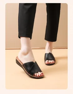Detailed view of women's black genuine leather flat slide sandals shown being worn