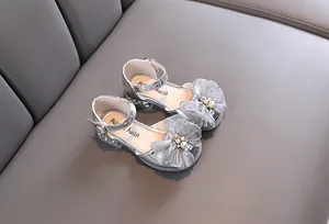Primer plano de zapatos de princesa plateados con lazo de malla floral y perlas