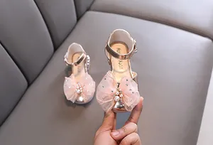 Detalle de zapatos de princesa oro rosa para niñas con gran lazo de malla.