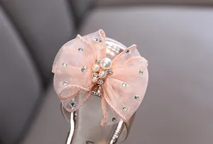 Detalle de un elegante lazo de organza rosa con perlas y diamantes en zapatos de niña
