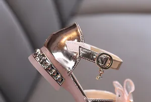 Detalle de zapato de baile oro rosa para niña con tacón de perlas y tira de hebilla