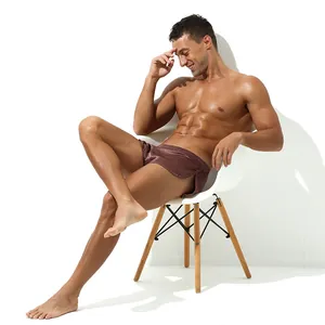 Model sitting in silky brown men's lounge boxers showing smooth fabric texture