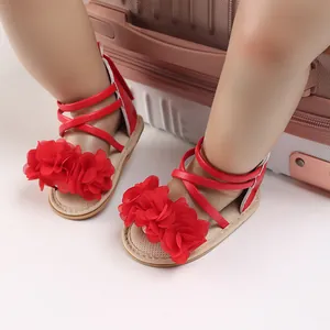 Dettaglio di sandali rossi per neonata con fiori di stoffa decorativi e suola in gomma.