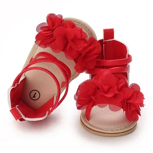 Primo piano di sandali rossi per bambina con fiori di chiffon e suole in gomma