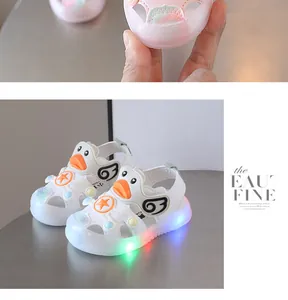 Cute white toddler light-up sandals with cartoon duck design and soft glowing LED soles.