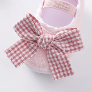 Close-up of pink infant princess shoe featuring a cute gingham bow-knot and soft fabric