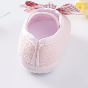 Close-up of pink baby girl princess shoe heel and red checkered bow decoration