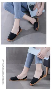 Detail view of black peep-toe slingback flat sandals worn by model in casual setting