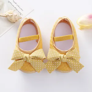 A detailed top view of yellow baby princess shoes featuring large polka dot bows.