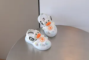 White light-up baby sandals with cute duck face and star design on a grey table