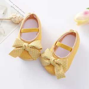 Detailed view of yellow baby princess shoes with polka dot bows and soft soles.