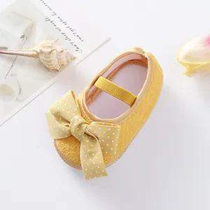 Detailed view of yellow baby princess shoe with a white polka-dot bow ornament