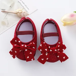 Detail of red baby girl princess shoes featuring large heart-print bows and soft soles