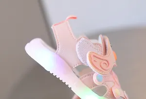 Macro detail view of pink baby sandals with glowing LED light sole and wing decorations