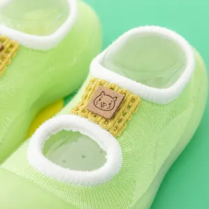 Close-up of mint green baby walking socks with cute cat patch and knit texture details