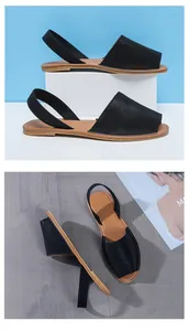 Close-up detail of black peep-toe flat sandals with backstraps and soft tan insoles.