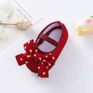 Detailed macro view of red baby princess shoes featuring a large bow with white heart prints.