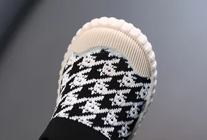 Close-up of children's breathable sneakers with black and white houndstooth pattern.