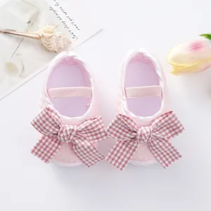 Close-up top view of pink baby princess shoes with checkered bows and soft soles for infants