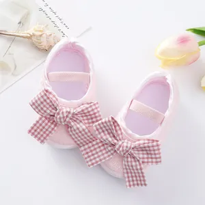 Detailed view of pink baby princess walking shoes featuring a red checkered bow decoration.