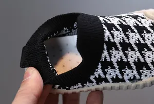 Close-up detail of black and white checkered children's knit sneaker with elastic heel