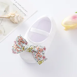 Close-up detail of a white infant princess walking shoe featuring a decorative floral bow