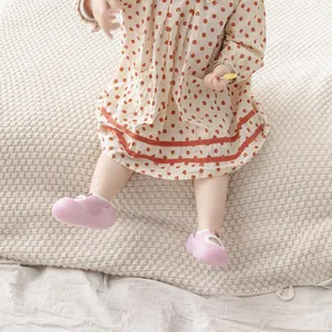 Close-up of pink anti-slip baby walker socks on toddler feet on a soft blanket.