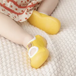 Detailed view of yellow baby walker shoes worn on feet with soft non-slip rubber soles