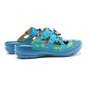 Détail macro de chaussures plates vintage en cuir bleu avec motifs floraux faits main et découpes