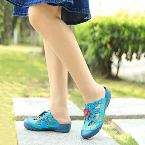 Gros plan de chaussures plates en cuir bleu ajouré avec des fleurs 3D colorées