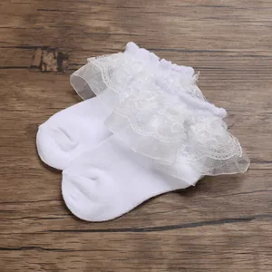 Close-up of elegant white breathable mesh infant socks with delicate lace ruffles