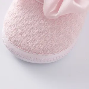 Macro view of pink baby shoe with textured fabric and silk bow detail