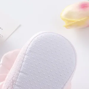 Detailed view of the white non-slip dotted sole on a soft pink baby princess shoe.
