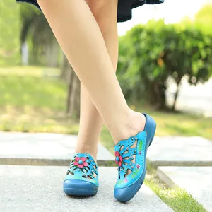 Gros plan de chaussures plates en cuir bleu avec fleurs 3D et motifs ajourés portées dehors.