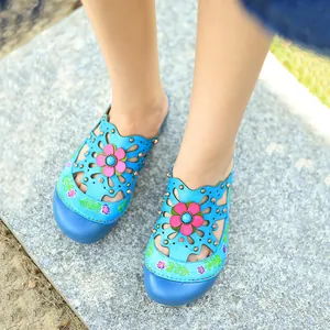 Vue détaillée de chaussures plates vintage en cuir bleu avec fleurs 3D aux pieds nus