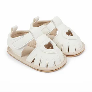 Close-up of white baby sandals featuring heart-shaped cutouts and soft leather texture