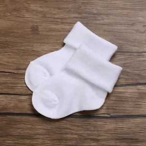 Close-up of soft breathable white cotton newborn baby socks on wooden background