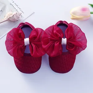 Top view of red newborn baby princess shoes with a large organza bow and lace details