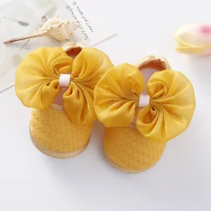 Close-up of yellow baby princess shoes with large organza bow and soft mesh fabric