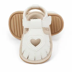 Close-up detail of white baby walking sandals featuring heart cutout and non-slip brown sole